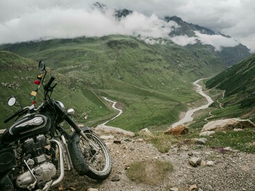 A motorcycle parked in front of lush green Himalayan mountains in Nepal, capturing a sense of adventure and stillness