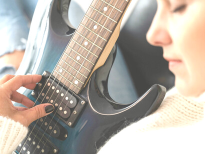 Mujer practica los acordes con un guitarra eléctrica