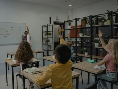 Una lezione frontale tradizionale: i bambini alzano la mano per rispondere alle domande