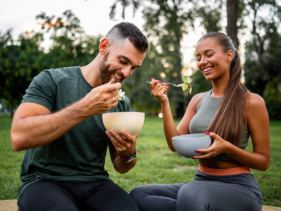 Happy athletic couple enjoying a healthy vegetable salad together after an intense workout session