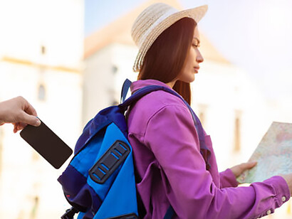 A tourist woman checks her map in a crowded street as a pickpocket steals her phone