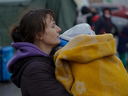 A woman holds her baby, wrapped in extra blankets in the cold; a scene from the Palanca-Maiaki-Udobnoe border crossing point, between the Republic of Moldova and Ukraine on 4 March 2022. Photos from the UN Women