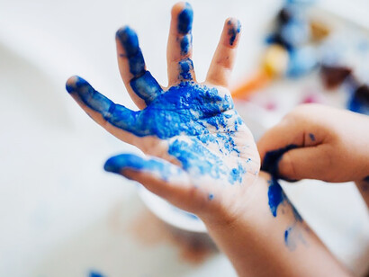 The creative essence as a child's hand adorned in blue paint diligently brings imagination to life through painting and arts & crafts