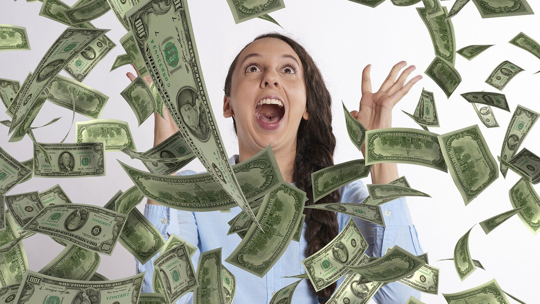An image depicting a woman with a cascade of money showering down around her
