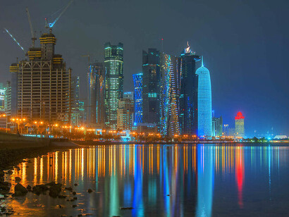 QIA (Qatar Investment Authority) y la diplomacia de inversión han sido instrumentos para abrir mercados y garantizar aliados. Reflejos del perfil urbano de West Bay en el agua, en junio de 2013, desde la Corniche de Doha,Qatar
