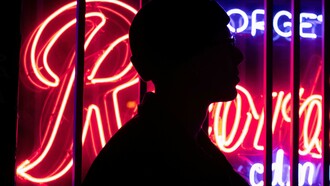 Silhouette of a person standing by neon lights at night