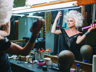 Surrounded by glitter and glam, the drag queen rehearses her performance, embodying the spirit of self-expression that is vital to the LGBTQIA+ community
