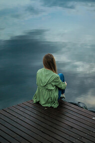 A woman sitting on wooden planks, deep in thought or reflection