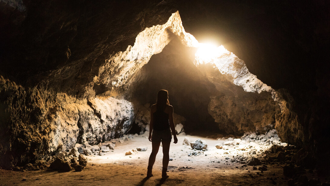 Mujer observa un halo de luz en el interior de una caverna en el desierto de Mojave, Estados Unidos