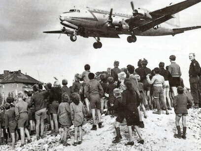 Pendant le pont aérien de Berlin en 1948, des avions américains, britanniques et français ont acheminé de la nourriture et d'autres marchandises à Berlin, qui était assiégée par les forces soviétiques. Sur cette photo, des enfants allemands se tiennent sur une colline et regardent passer un avion américain