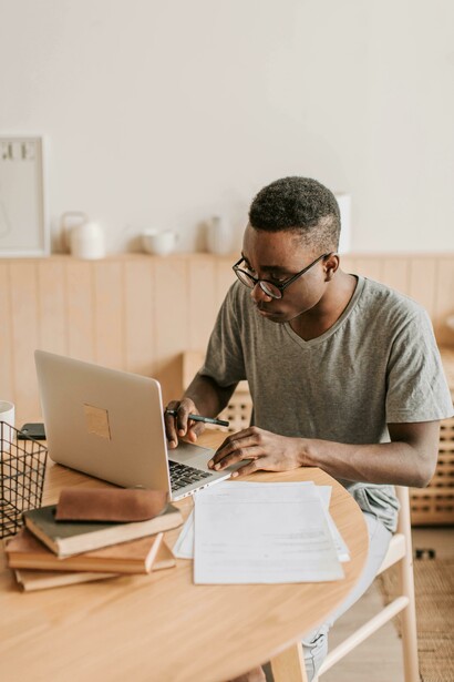 Academic writing in progress as a man in a gray shirt works on his laptop