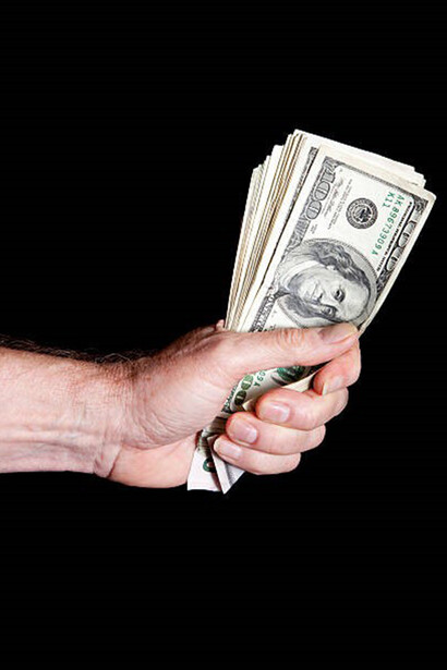 A person tightly gripping a bundle of banknotes