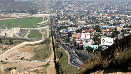 A small fence separates densely-populated Tijuana, Mexico, right, from the United States in the Border Patrol's San Diego Sector. Construction is underway to extend a secondary fence over the top of this hill and eventually to the Pacific Ocean