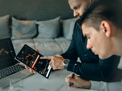 Homens avaliam índices econômicos. Para os economistas austríacos, o mercado não é um estado de equilíbrio estático, mas um processo dinâmico de descoberta. Hayek, em particular, destacou o papel dos mercados na coordenação das ações dos indivíduos. O mercado permite que informações dispersas sejam compartilhadas e utilizadas de forma eficiente, promovendo a inovação e a adaptação. A ideia de que o mercado é um processo de descoberta reflete a crença de que a economia não pode ser planejada de forma centralizada, pois a complexidade e a incerteza dos mercados exigem flexibilidade e adaptação contínua