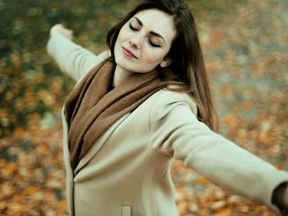 A woman twirling in a park with eyes closed expressing her liberation