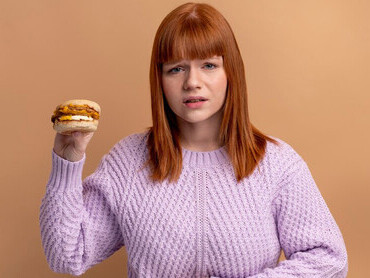 A woman with food intolerance is attempting to eat something but is experiencing a stomach ache due to her dietary restrictions