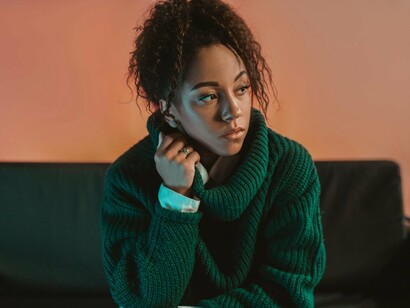 A young woman sitting quietly with distant thoughts, representing the emotional exhaustion of modern uncertainty