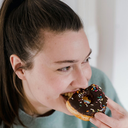 Mulher comendo donut. O consumo excessivo de glicídios pode levar a um comportamento semelhante ao vício