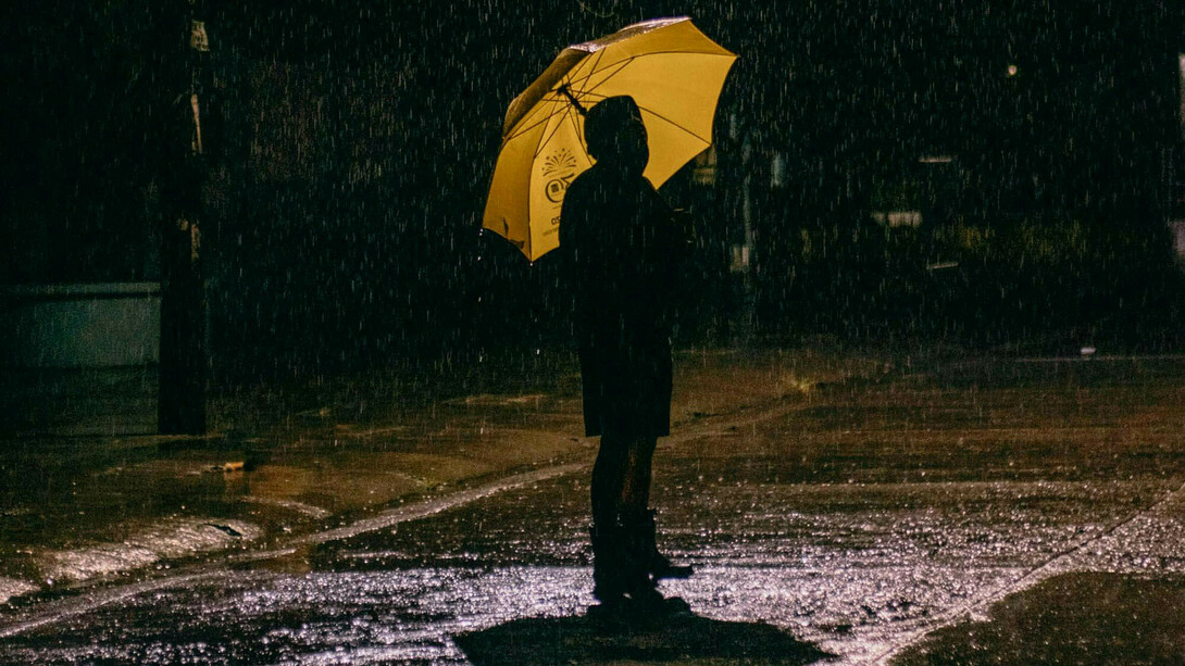 Ein Mann steht mit einem Schirm im Regen