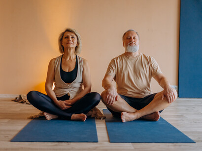 Casal da terceira idade respirando profundamente em posição de meditação