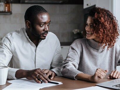 A husband and wife discussing household finances with focus and trust, symbolising the strength of partnership in achieving long-term success