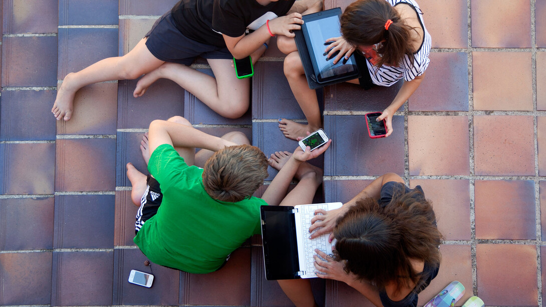 Niños jugando con ordenadores, móviles y tabletas
