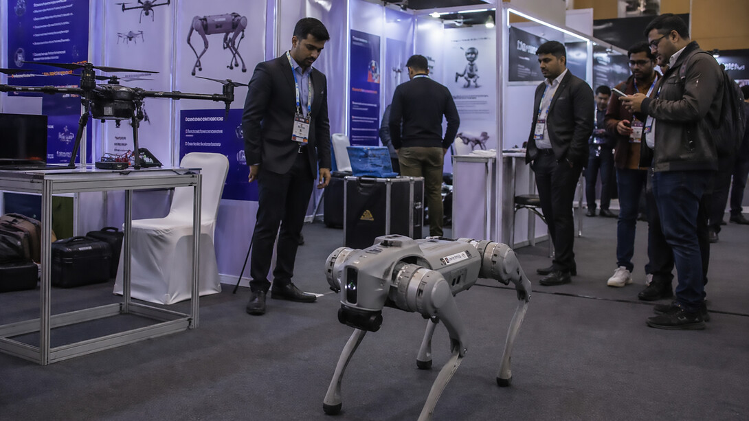 A robotics demonstration at a crowded technology exhibition, where a quadruped robot and surrounding displays highlight the fine line between innovation, presentation, and perception in modern AI showcases