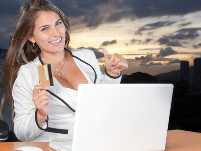 With a satisfied smile, the woman confidently completes an online purchase, holding a credit card in her hand as she indulges in a seamless and convenient shopping experience, showcasing the ease and benefits of digital transactions