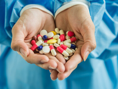 A woman’s hand gently holds the medicine pills in her palm
