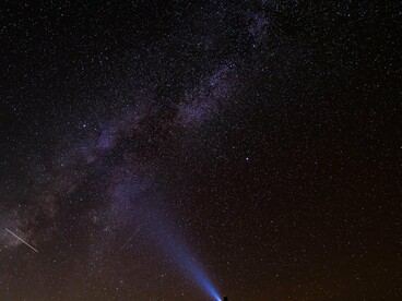 A figura iluminada contempla o universo como quem procura respostas muito além da Terra. O brilho da lanterna contrasta com a vastidão do céu, numa imagem que dialoga com a jornada solitária do protagonista. Observar as estrelas continua sendo um dos gestos mais humanos do cinema e da ciência