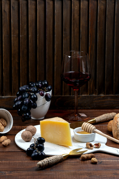 A slice of cheese served alongside grapes and wine