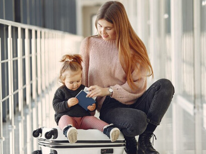 A mother and her daughter with luggage at the airport terminal