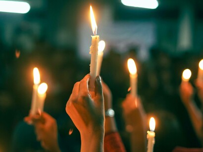 Group of people hold candles in unison