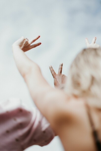 Man and woman stretching out arm to hold peace sign