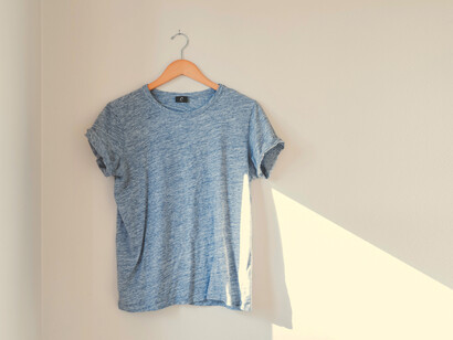 Camiseta celeste en una percha guindada en la pared