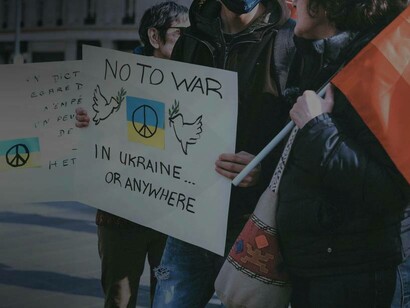 Protestors march in Amsterdam, Netherlands with signs that read "no to war in Ukraine or anywhere"