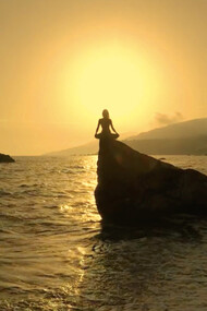 As the sun sets in a golden embrace, she finds solace on the rock, reminding us that moments of silence can lead to profound self-discovery