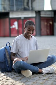 Estudante sentada com computador na rua