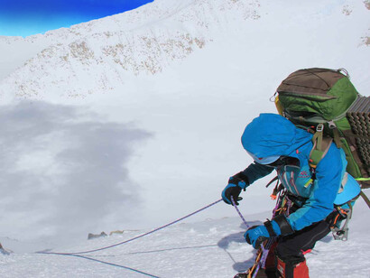 Pakistani mountaineer Samina Baig pulling a climbing rope on a deeply snowy part of the mountain