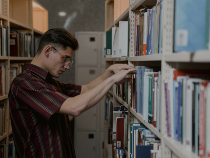 Una mujer buscando entre los libros de una biblioteca su próxima lectura