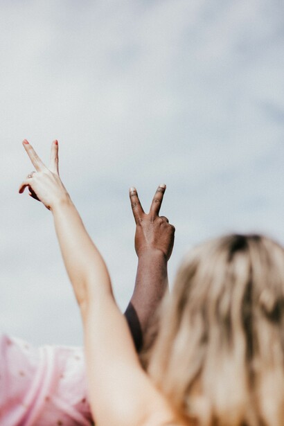 Man and woman with peace sign pointed to the clouds