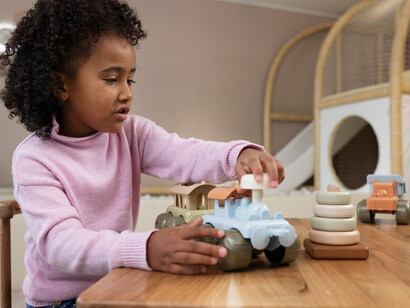 An African American girl playing with gender-neutral, eco-friendly toys indoors