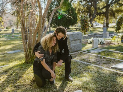 Um homem e uma mulher chorando no cemitério