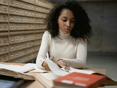 A woman studies in a library, her table filled with books
