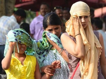 People in India walk through the streets, covering their faces and heads to protect themselves from the extreme heat