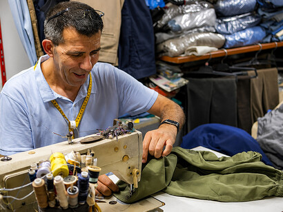 Skilled tailor repairing clothing in a workshop, showcasing visible mending techniques and traditional textile craftsmanship