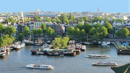 Vista de Amsterdã, Holanda. Ela ligou o motor. O barco, lento como o meu olhar, atravessava pequenas ondinhas formadas pelo vento e pelo balançar do barquinho