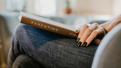 A nurturing woman engrossed in a parenting book, finding guidance within its pages