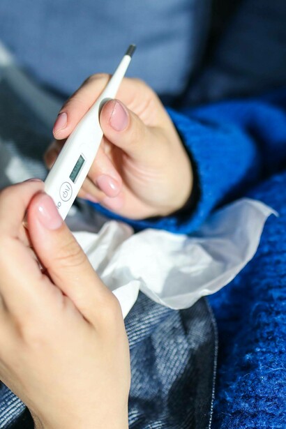 Woman checks for fever with a thermometer