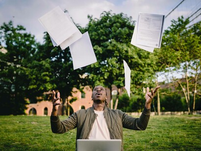 A man jubilant and celebrating his success by tossing papers in the air